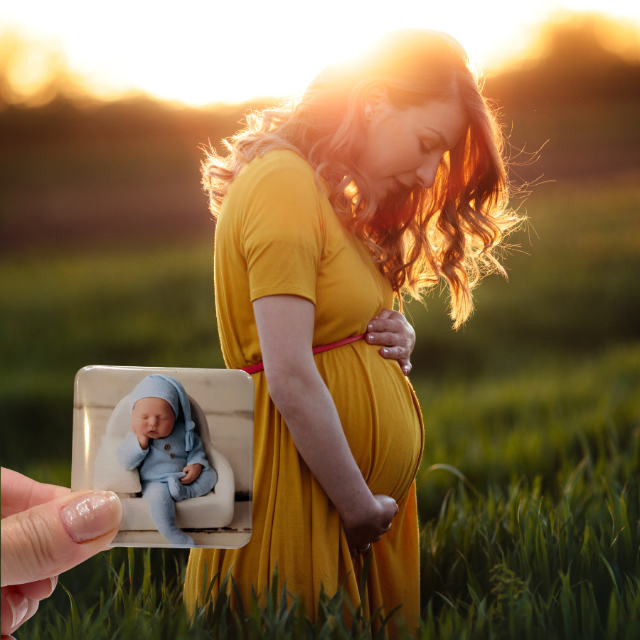Hand holding a 2 x 2 photo magnet of a newborn in front of an expectant mother at sunset.