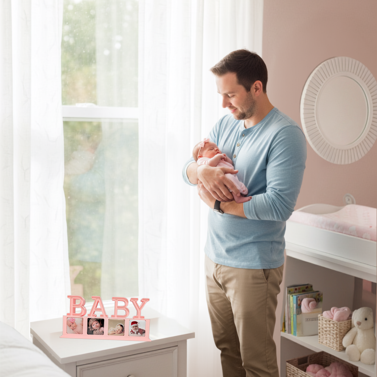 Man holding a newborn in a blush-pink nursery, with a pink BABY photo magnet display on a white dresser.