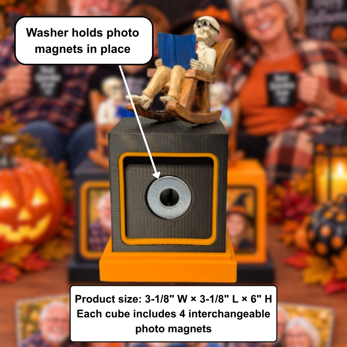A Halloween memory cube decorative photo frame display - magnet holder product shown in a festive, Halloween-themed setting with a blurred background of people and pumpkins. The product is a black and orange cube with a rocking skeleton figurine sitting on top reading a blue book, and a silver photo magnet mounted in the front center.
