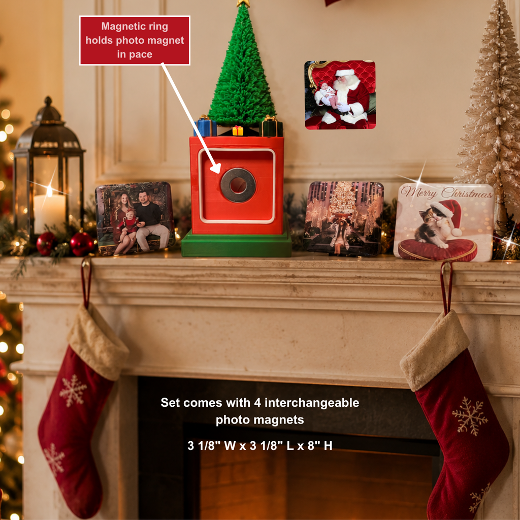 A holiday-themed display on a fireplace mantel featuring a red and green magnetic photo magnet holder with a small green Christmas tree on top. White text labels point to the product, including 'Magnetic ring holds photo magnet in place' and 'Set comes with 4 interchangeable photo magnets 3 1/8" W x 3 1/8" L x 8" H'.