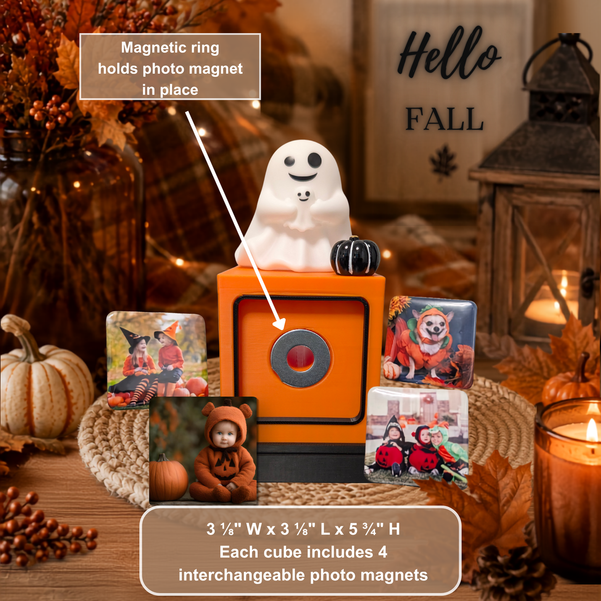 An orange decorative photo cube display with a white ghost figure on top, surrounded by four sample square photo magnets and a text callout explaining that the magnetic ring holds the photo magnet in place. The scene is styled in autumn with pumpkins, candles, and fall decor.