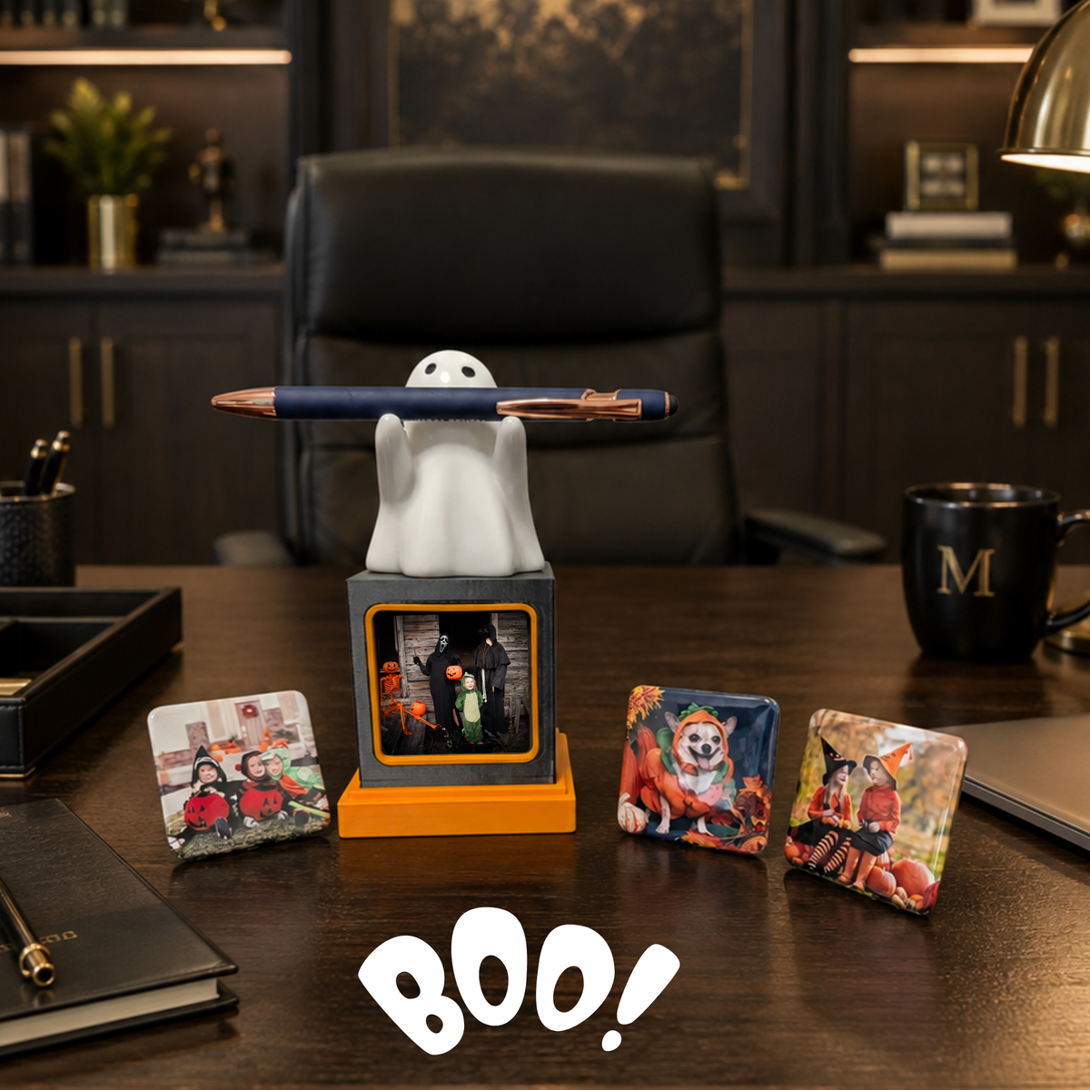 A Halloween-themed photo frame display set on a dark wooden office desk. A ghost-shaped holder holding a blue pen, with a small photo magnet in the front and three additional photo magnets on the desk.