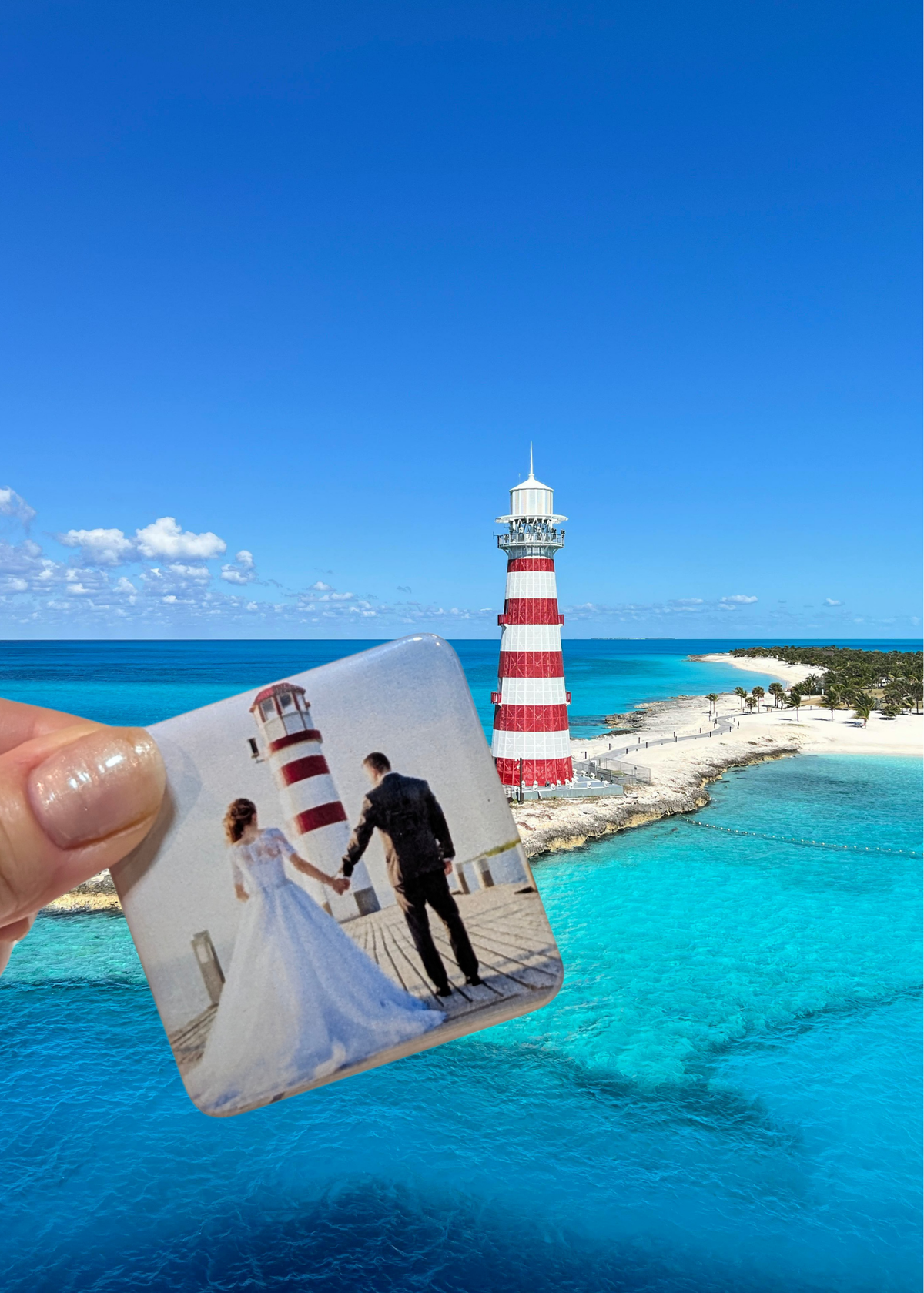Hand holding a wedding photo magnet in front of a tropical beach scene with a lighthouse.