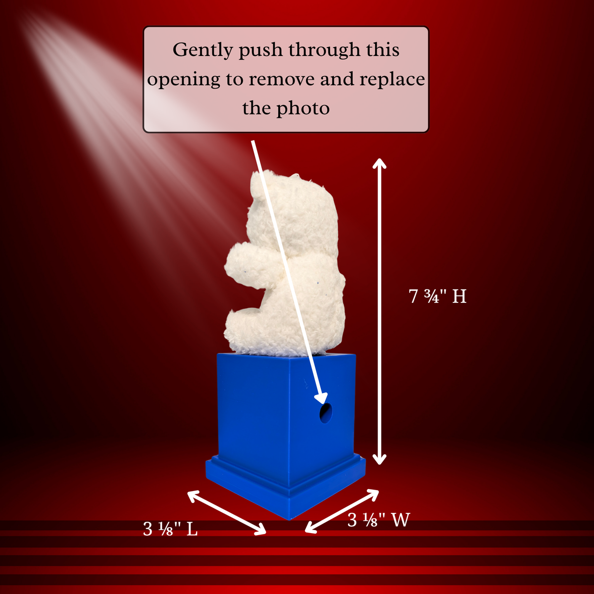 A white teddy bear sitting on a blue memory cube , with measurement arrows indicating 7 3/4 inches high, 3 1/8 inches wide, and 3 1/8 inches deep. Text at the top says to gently push through an opening to remove and replace the photo, on a dark red gradient background.