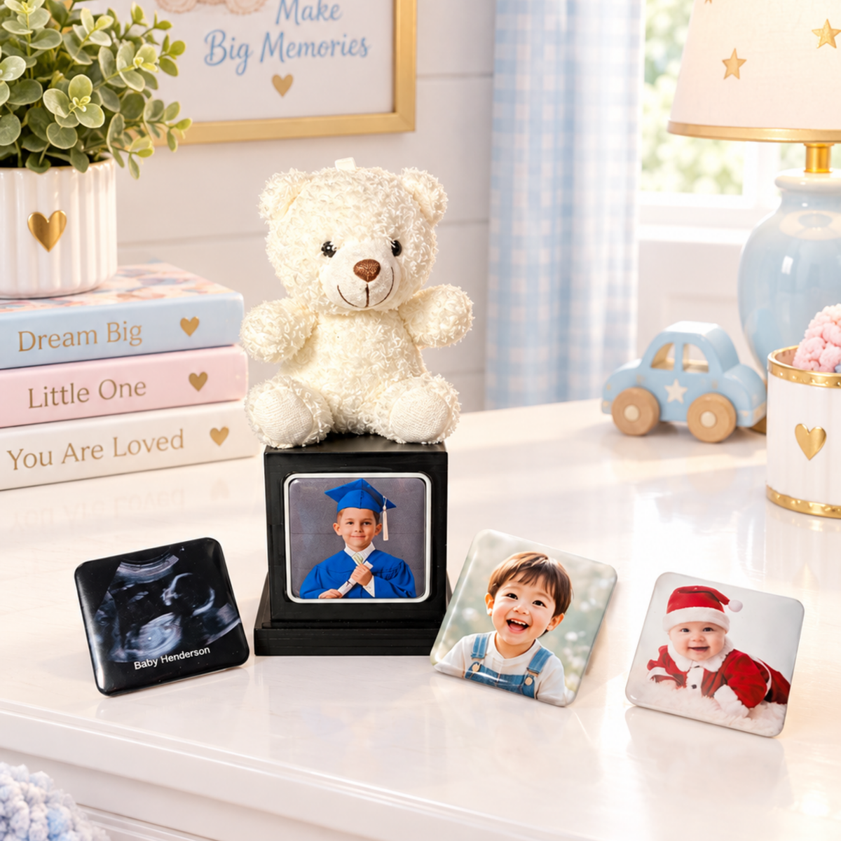 A personalized photo display set on a white tabletop in a softly styled room. A white teddy bear sits on a black memory cube with a photo magnet inside and three photo magnets displayed around it. 